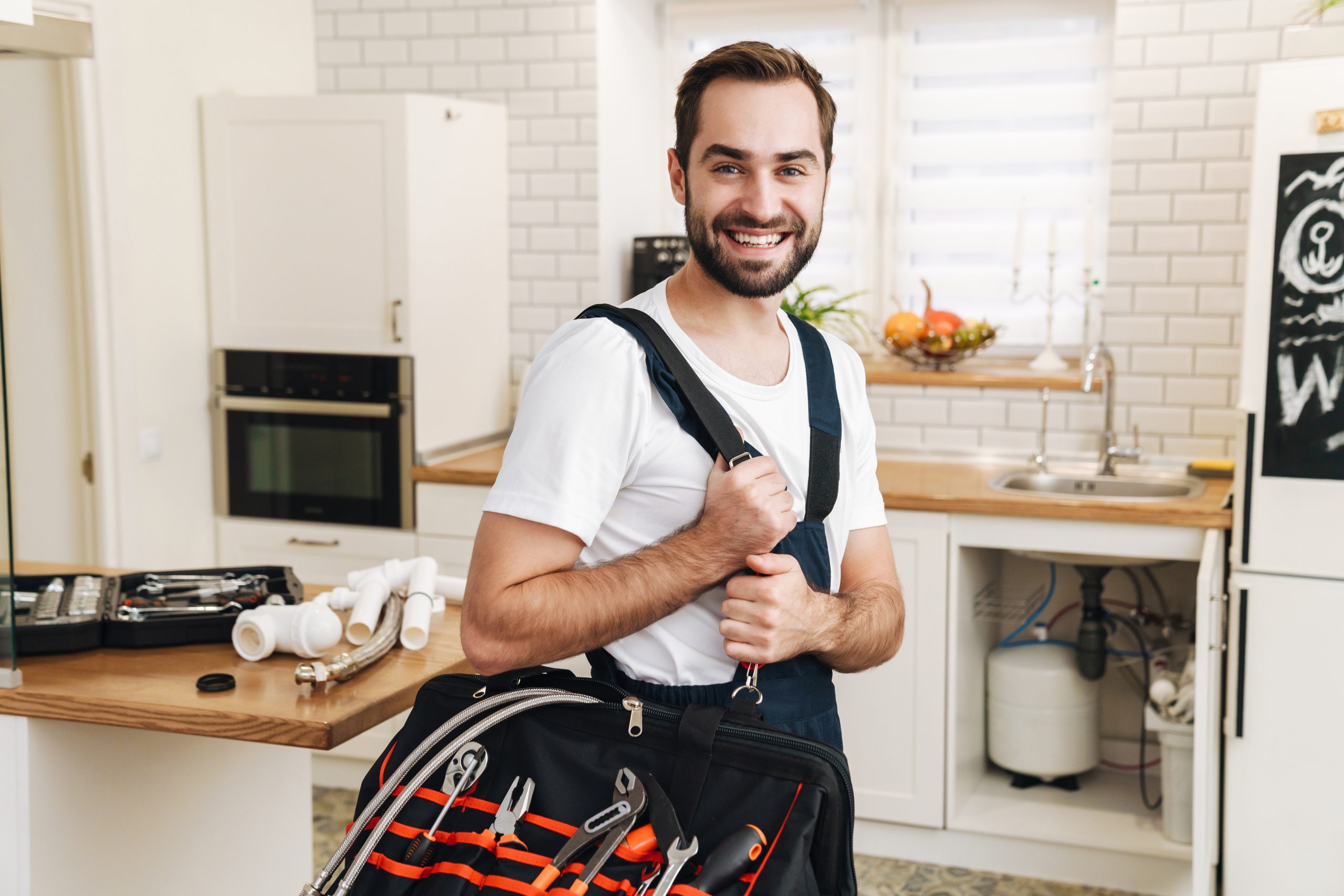 image of plumber man smiling and holding bag with equipment in a