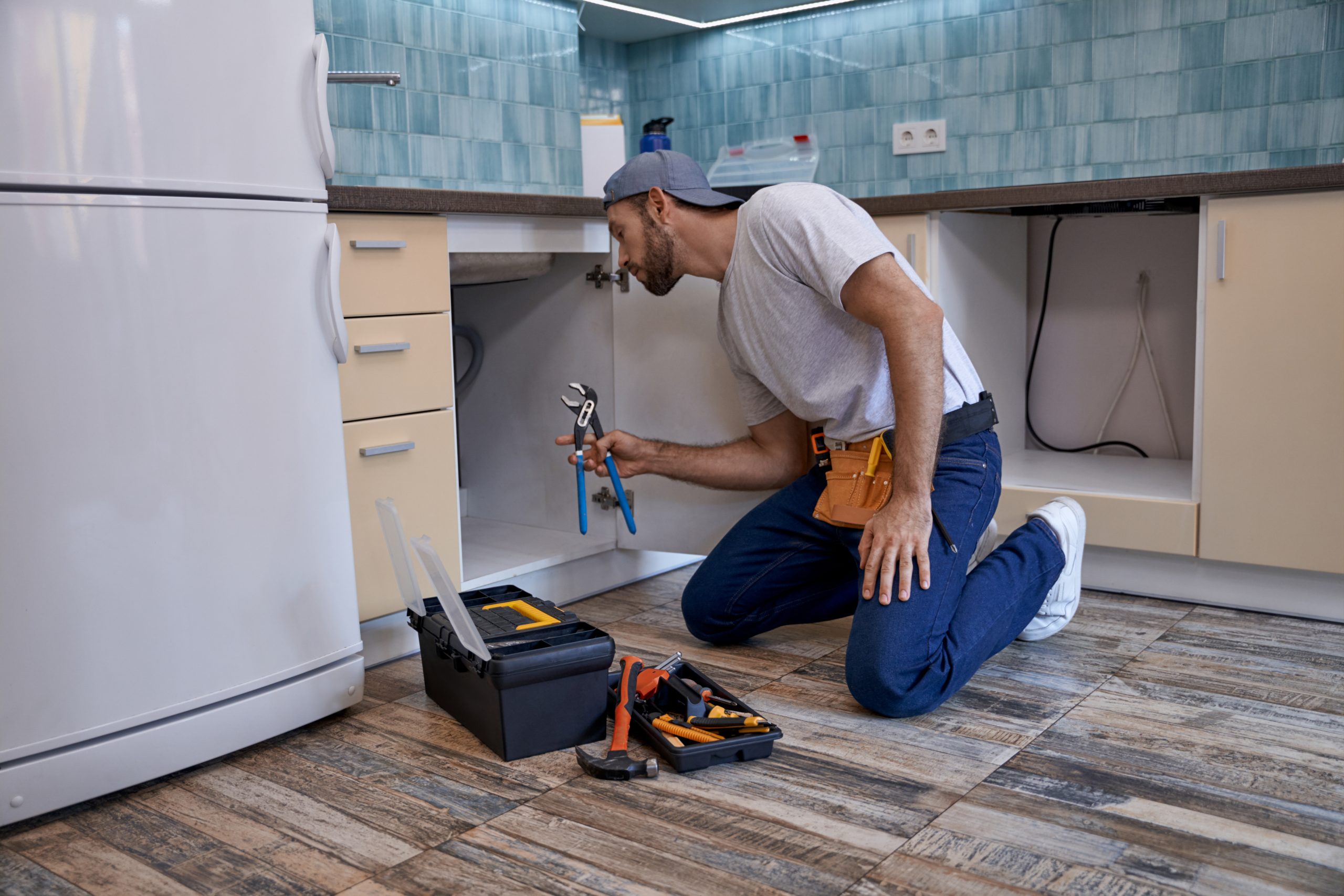 young caucasian man working with wrench in kitchen drawer