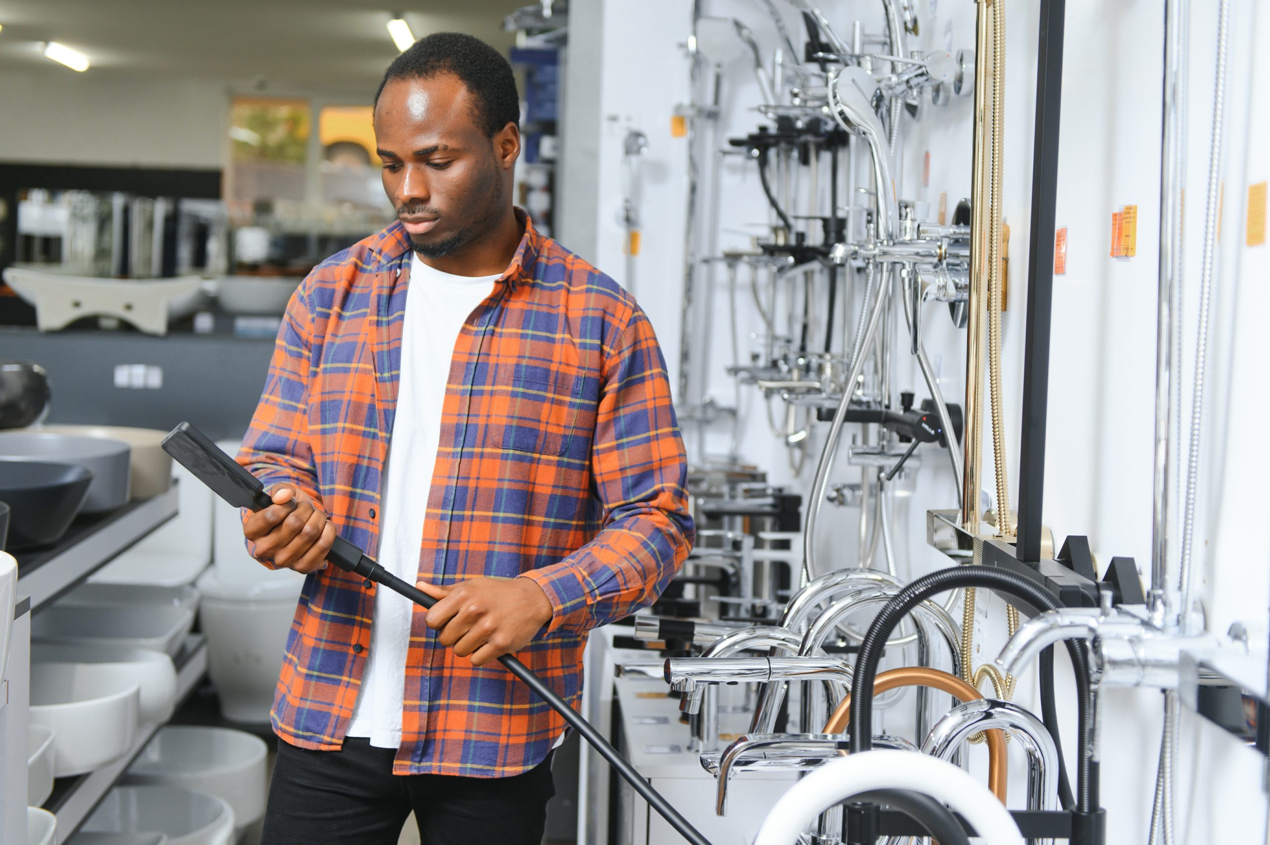 a large selection of water faucets. african american man chooses a products in a sanitary ware store